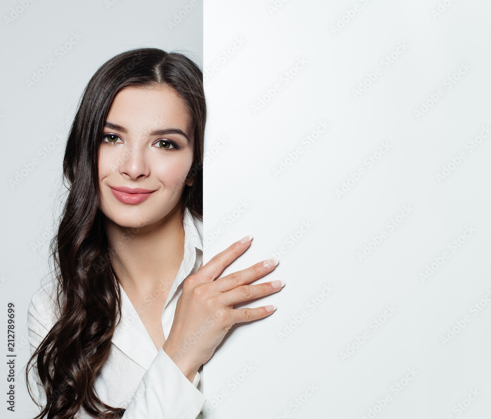 Young beautiful brunette woman with white blank paper banner background. Happy smiling woman. Advertising marketing, business and education concept. Young beautiful brunette woman with white blank paper banner background. Happy smiling woman. Advertising marketing, business and education concept.