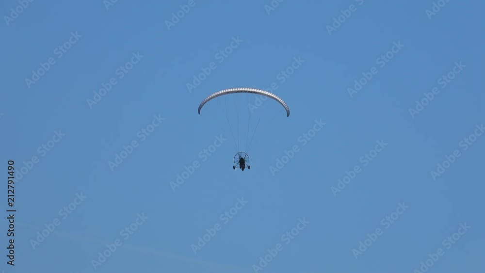 Man with a parachute, motor flying in the blue sky Man with a parachute, motor flying in the blue sky
