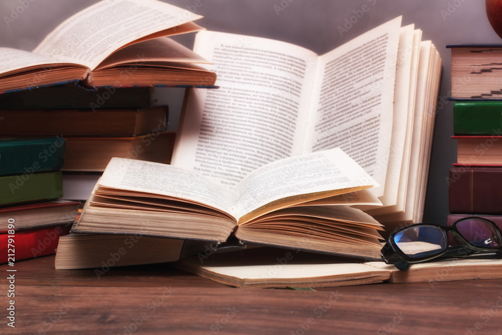 Stack of open books on the table in the background of a school blackboard. Back to school. Stack of open books on the table in the background of a school blackboard. Back to school.