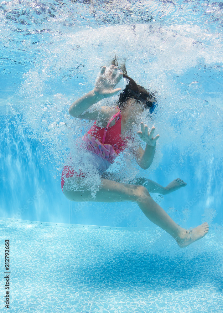 Sporty little girl in a red swimsuit jumps in the pool. Underwater