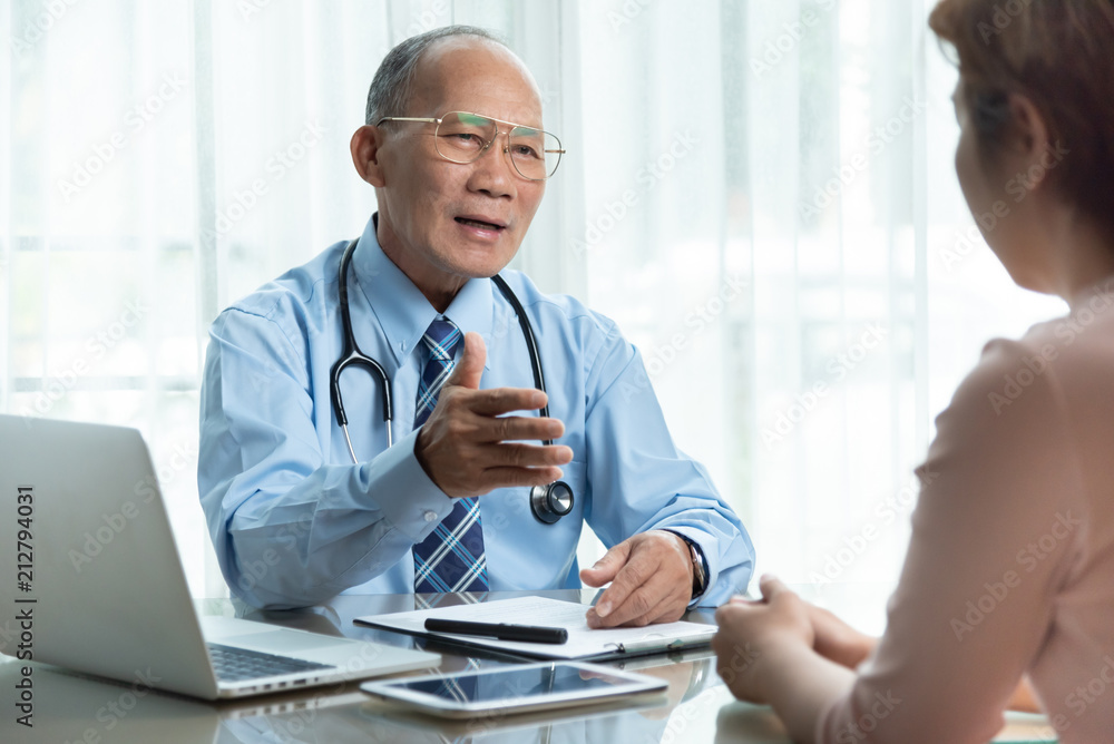 Fototapeta premium Senior Male doctor in blue shirt talking with female patient.