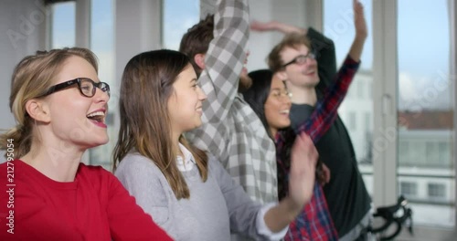 Five good mooded people in a modern office doing a la ola wave together