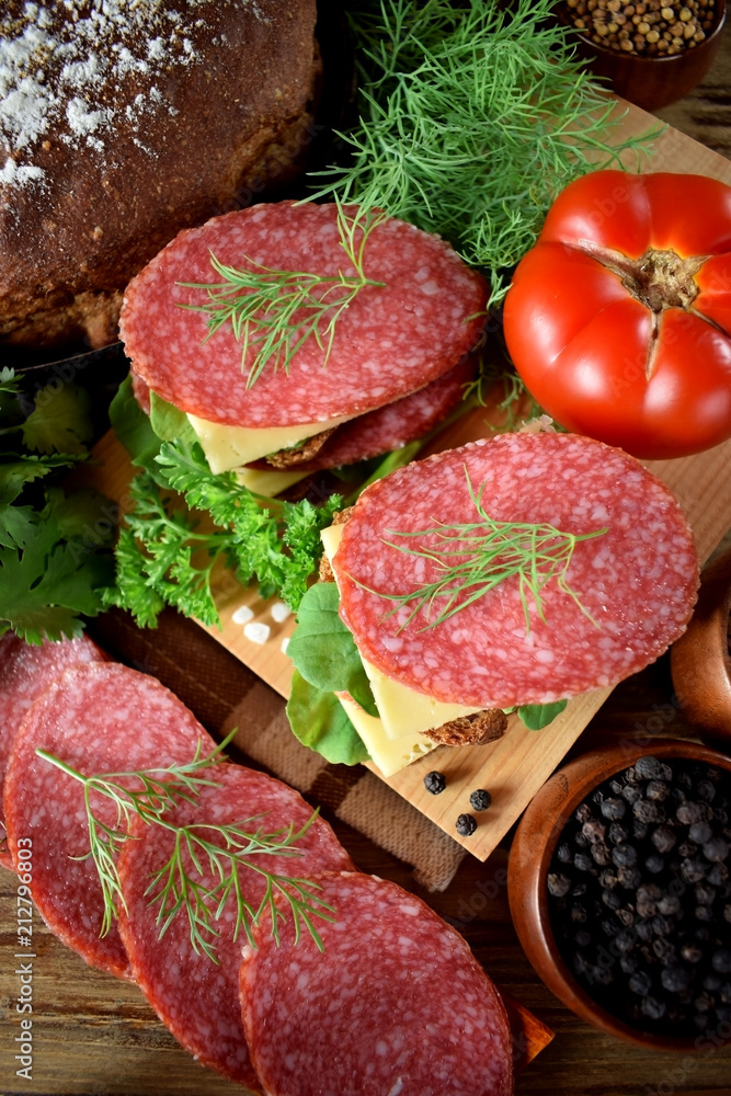 Sandwiches with salami, cheese and arugula salad surrounded by the ingredients Sandwiches with salami, cheese and arugula salad surrounded by the ingredients