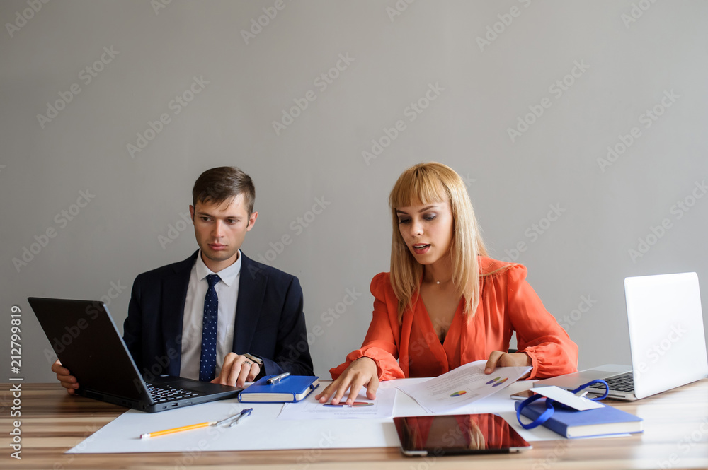 A business woman and man at a office desk working at the projec A business woman and man at a office desk working at the projec