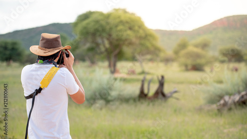 Young man traveler and photographer taking photo of wildlife animal in African safari. Wildlife photography concept