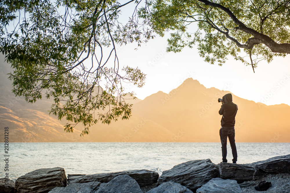 Φωτογραφία Young male photographer looking at scenery of Lake Wakatipu during golden hour s