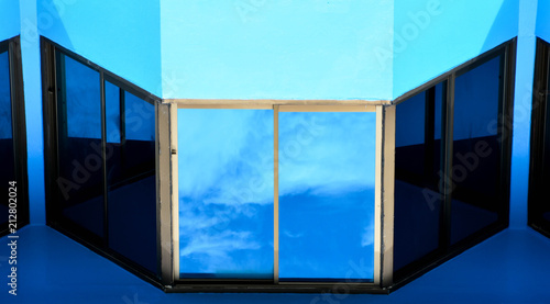 glass window with reflection from the sky at blue concrete building