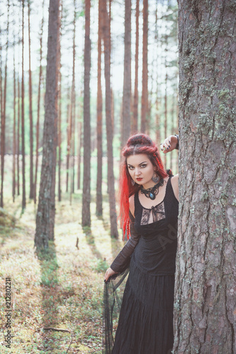 Beautiful woman witch with red hair in the forest