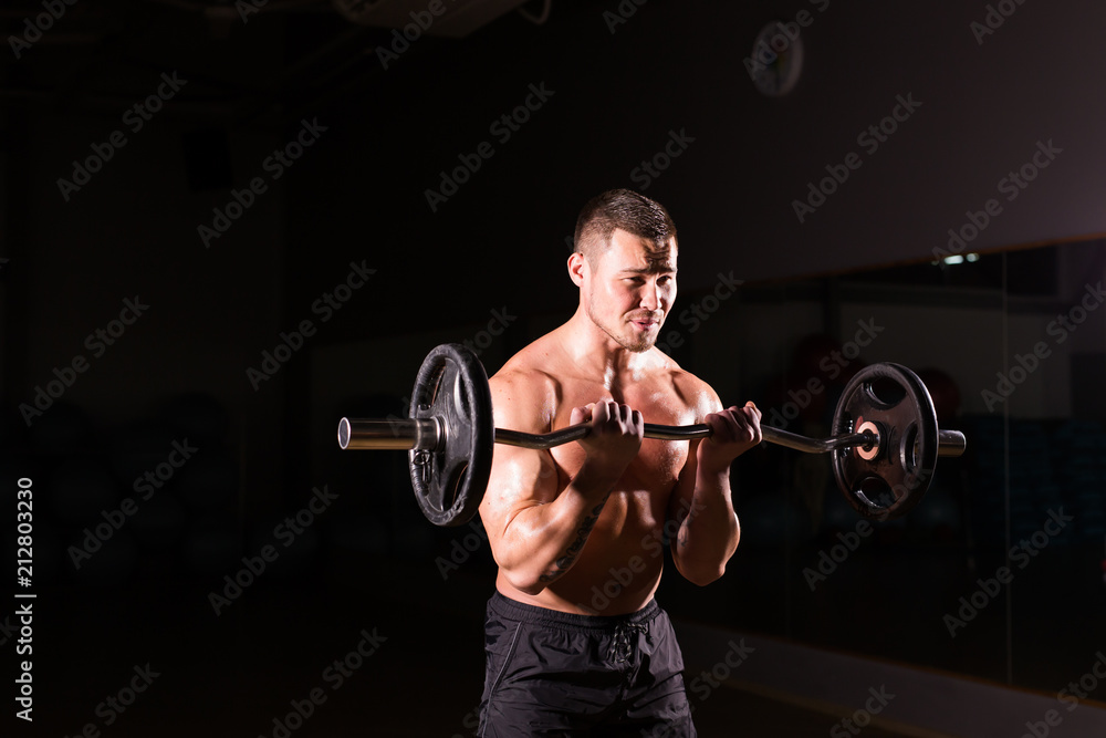 Handsome power athletic man with barbell. Strong bodybuilder with six pack, perfect abs, shoulders, biceps, triceps and chest Handsome power athletic man with barbell. Strong bodybuilder with six pack, perfect abs, shoulders, biceps, triceps and chest