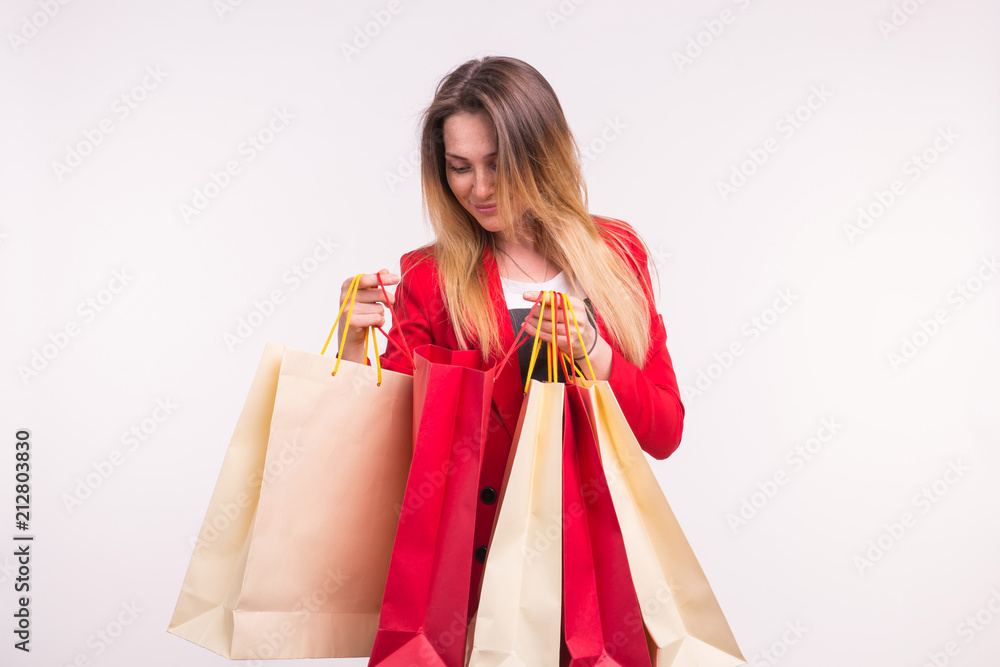 Portrait of happy stylish young woman with shopping bags in red suit