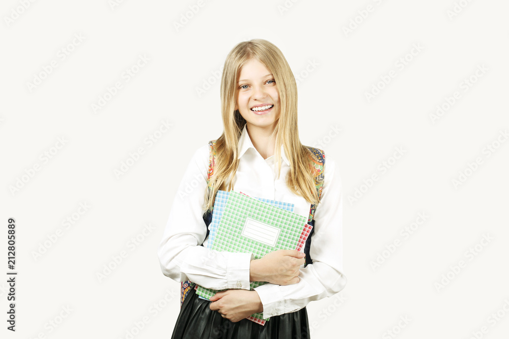 Beautiful blonde teenage girl with charming smile in schoolgirl uniform wearing pleated skirt, white shirt, backpack, holding notebooks. Back to school sale concept. Background, copy space, close up. Beautiful blonde teenage girl with charming smile in schoolgirl uniform wearing pleated skirt, white shirt, backpack, holding notebooks. Back to school sale concept. Background, copy space, close up.