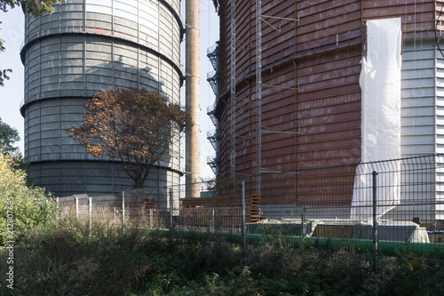 View of the huge factory cisterns behind the fence in early autumn in Europe