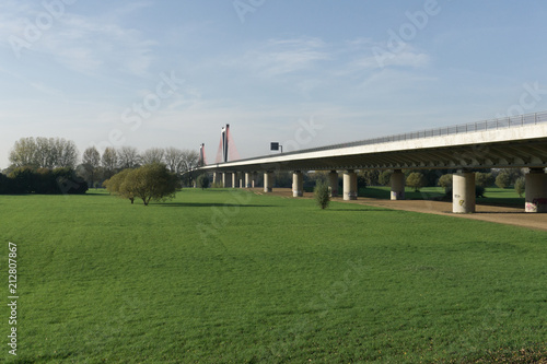 A field with an automobile bridge passing over the river on a summer day