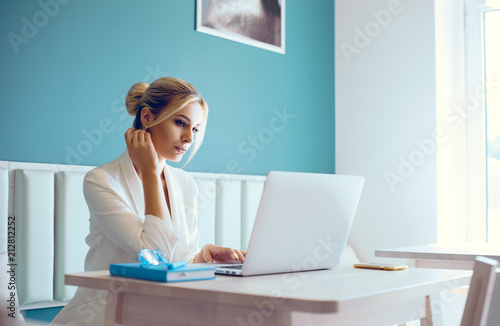 Beautiful girl working out a plan of the project and concept. Girl paints a website design on a laptop. student prints a message on the phone in the messenger. Development. Digital marketing