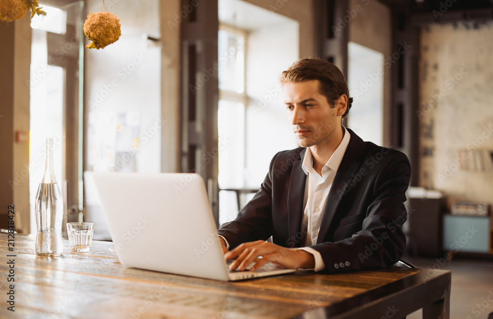 Fototapeta premium Young man drawing template for the web site associated with digital marketing, current trends and tendencies of UX / UI design. Businessman who rules his company remotely, like a freelancer