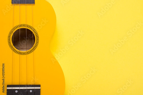Photos Body of a bright yellow ukulele guitar against a yellow background (minimalism s