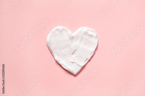 Heart shape from cream in pink background. Skin care.