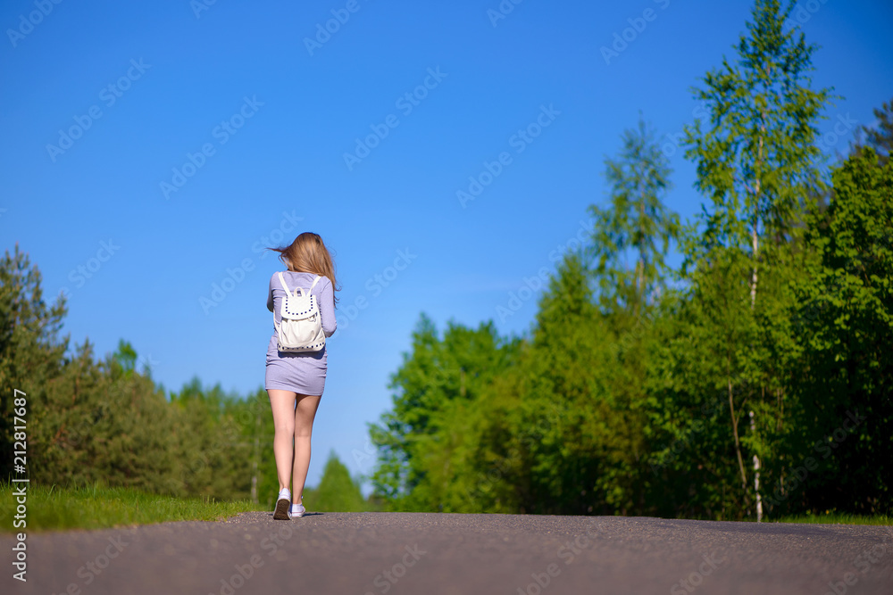 girl walks on the road on a summer day