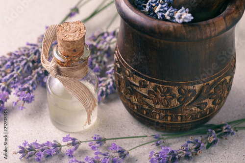 Fototapeta Naklejka Na Ścianę i Meble -  Lavender oil in a transparent bottle with flowers and a mortar for grinding the ingredients