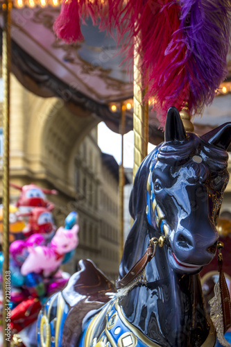 Fototapeta Naklejka Na Ścianę i Meble -  Beautiful colorful black wooden horse with red feathers on head on carousel merry-go-round, amusement on Piazza della Repubblica,  Florence, Italy