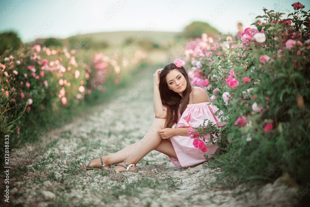 Portrait of beautiful woman is sitting in pink blossom garden. The concept of perfume advertising. Portrait of beautiful woman is sitting in pink blossom garden. The concept of perfume advertising.