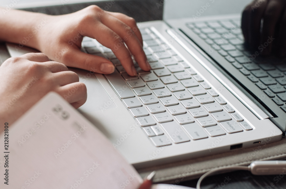 Woman working on computer and making notes in th notebook Woman working on computer and making notes in th notebook