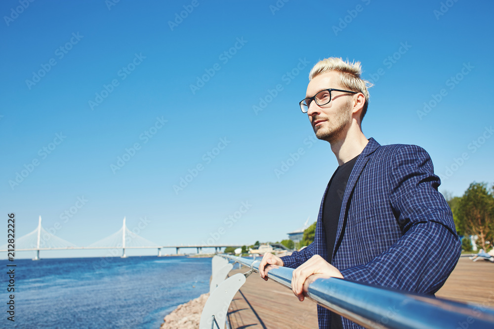 Handsome man resting at�quay�handrail