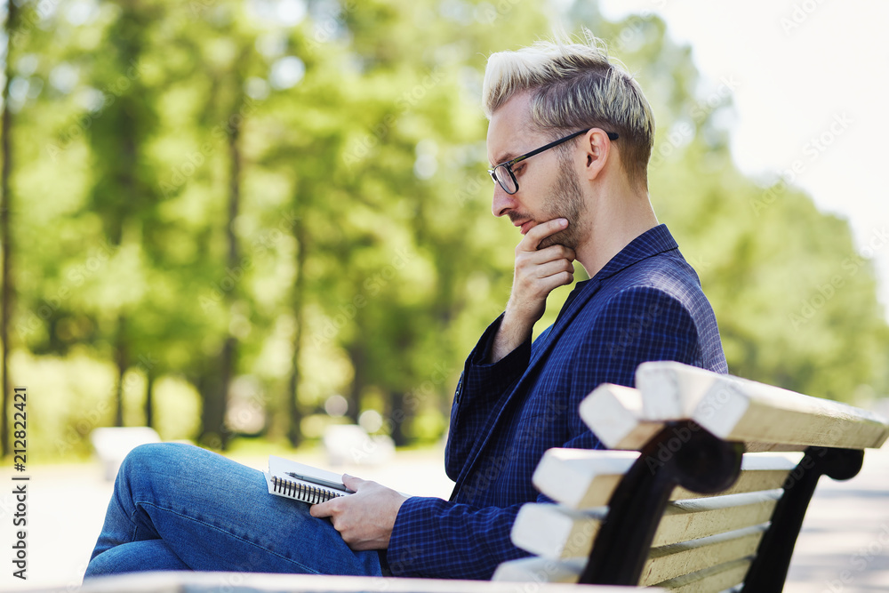 Fototapeta premium Man with notebook thinking sitting on bench