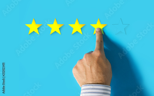 Hand choosing 4 yellow stars on blue background - Good feedback concept