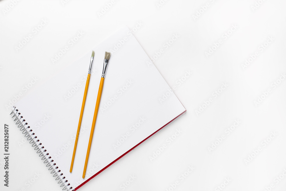Drawing notebook and brushes on white surface Drawing notebook and brushes on white surface