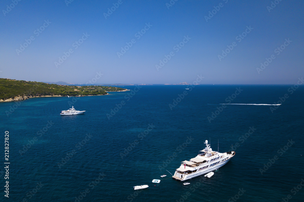 Aerial view of a luxury yacht on a turquoise and transparent sea. Emerald Coast, Mediterranean sea, Sardinia, Italy.