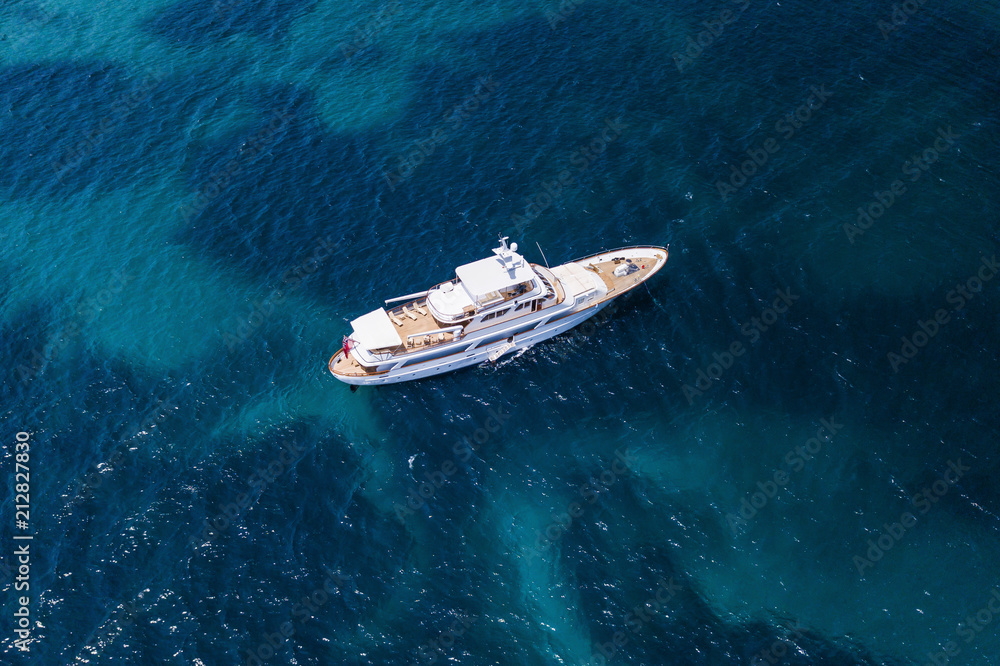 Fototapeta premium Aerial view of a luxury yacht on a turquoise and transparent sea. Emerald Coast, Mediterranean sea, Sardinia, Italy.