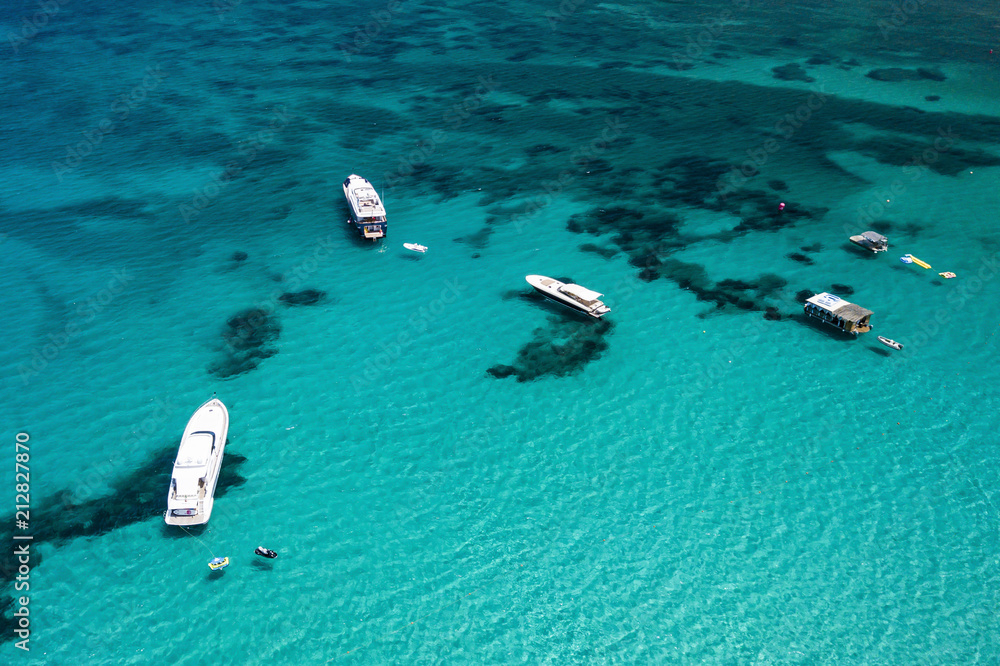 Aerial view of some yachts and sailing vessel on a turquoise and transparent sea. Emerald Coast, Mediterranean sea, Sardinia, Italy.