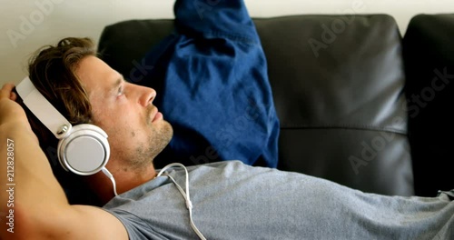 Man listening music on headphones living room 4k