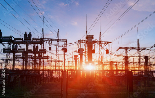distribution electric substation with power lines and transformers, at sunset