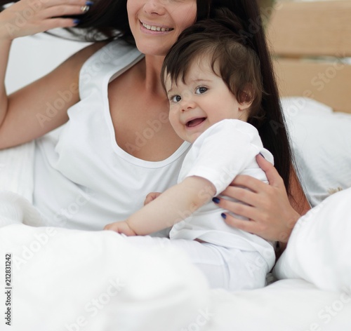 Portrait of a beautiful mother with her baby in the bedroom