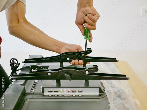 Canvas Print A technician is installing a wall mount on a television getting it ready to be p