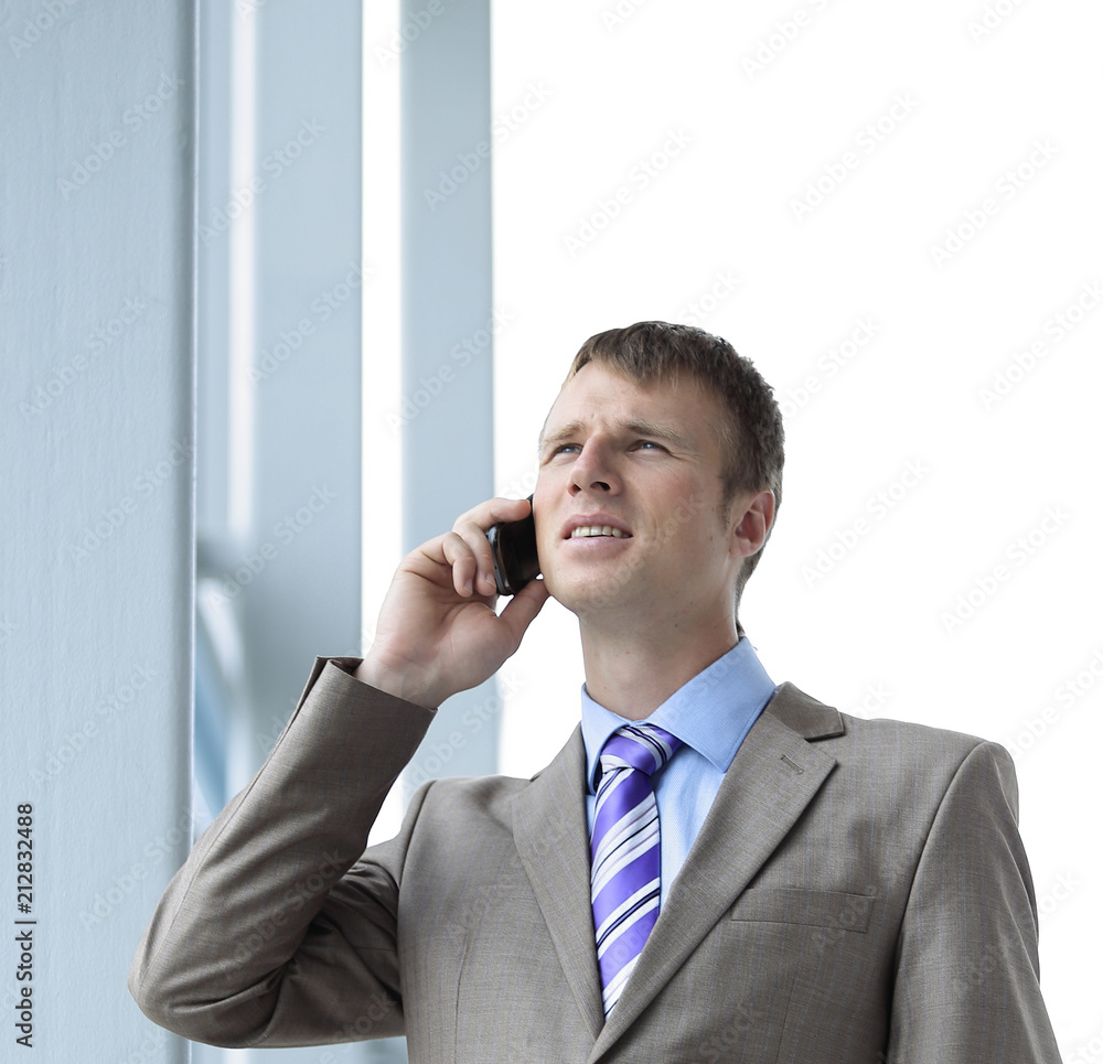 Businessman at the window talking on the phone Businessman at the window talking on the phone