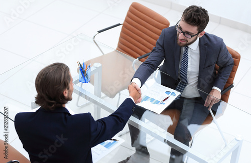 handshake of business partners sitting at their Desk © ASDF