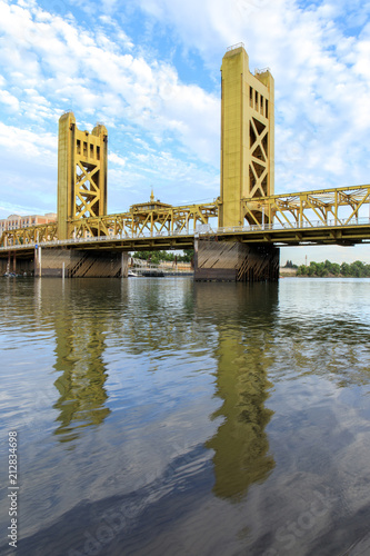 Tower Bridge with wispy sky reflected on the Sacramento River. Sacramento and Yolo Counties, California, USA.