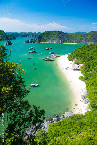 a view of a sandy beach and Halong bay with some boats shot from the top of Monkey island