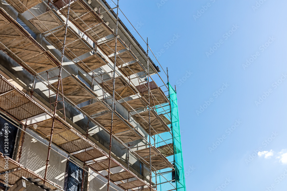 reconstruction of old city building. scaffolding near building facade against blue sky background