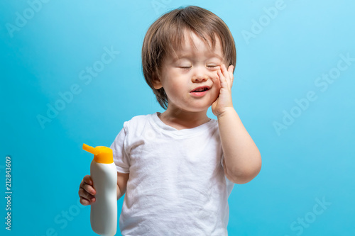Toddler boy with a bottle of sunblock on a blue background