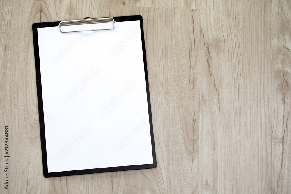 Clipboard with a blank sheet of paper on wooden table. Clipboard with a blank sheet of paper on wooden table.