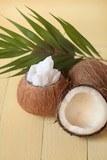 Coconut oil.  organic natural coconut oil  set, half fresh coconut and a palm leaf on a light yellow wooden plank background.
