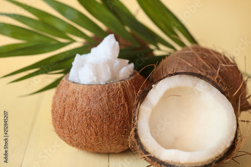 Coconut oil.pure natural coconut oil set, half fresh coconut and a palm leaf on a light yellow wooden plank background.
