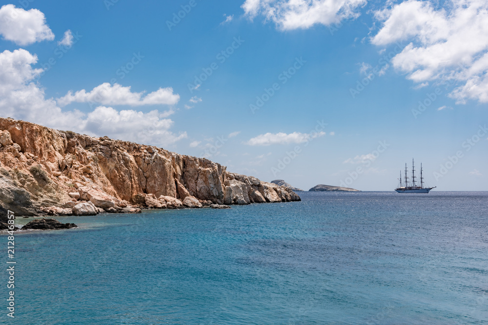 View of sailing ship from rugged rocky coastline