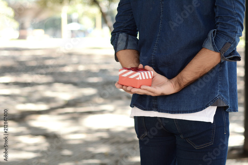 Man holding a gift box behind his back.