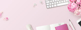 feminine banner or shop header with office / writing supplies, technical gadgets, smartphone and a bunch of pink flowers on a pink background - copyspace for your text and branding - top view