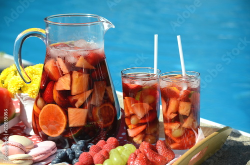 Pool party with sangria pitcher, fruit cocktails and refreshments by the swimming pool. Summer lifestyle, fun and relaxation theme. Stay at home vacation.